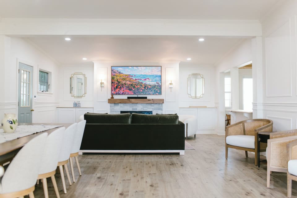 This bright communal space at Greenleaf Inn features a large dining table, fireplace, smart TV, and elegant coastal decor—perfect for relaxing, dining, or gathering in beautiful Boothbay Harbor.
