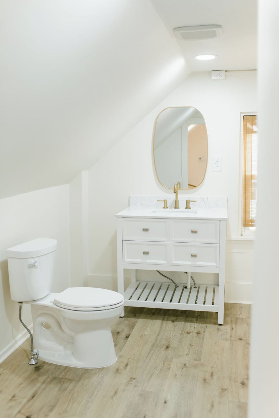 Room 5's ensuite bathroom at the Greenleaf Inn in Boothbay Harbor features a modern vanity, brass fixtures, and sloped-ceiling charm—blending coastal style with comfort.