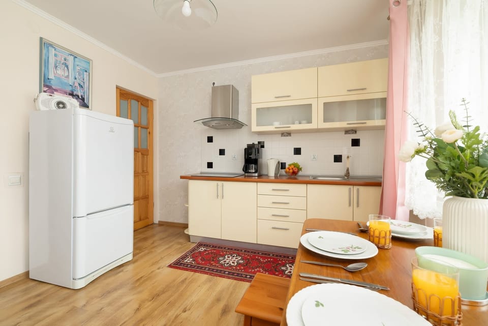 Functional kitchen area with dining area and large fridge.
