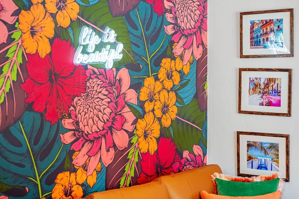 The cozy yet stylish living area invites you to unwind with plush seating, tropical-inspired artwork, and large windows that let in an abundance of natural light.