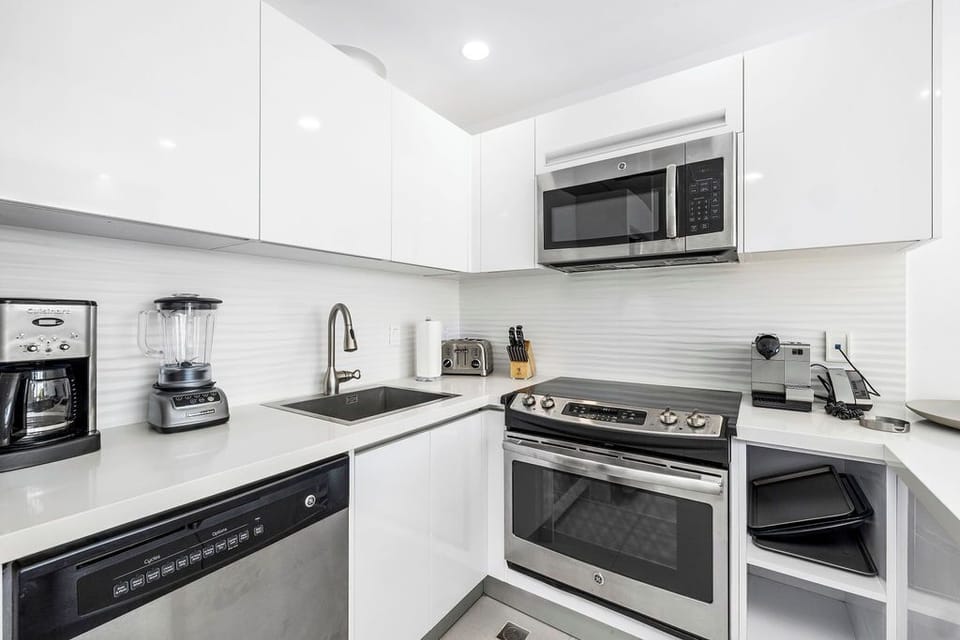 Your modern kitchen is outfitted with everything you need to whip up delicious meals—stainless steel appliances, a coffee maker, blender, and gleaming white countertops that make cooking a joy.