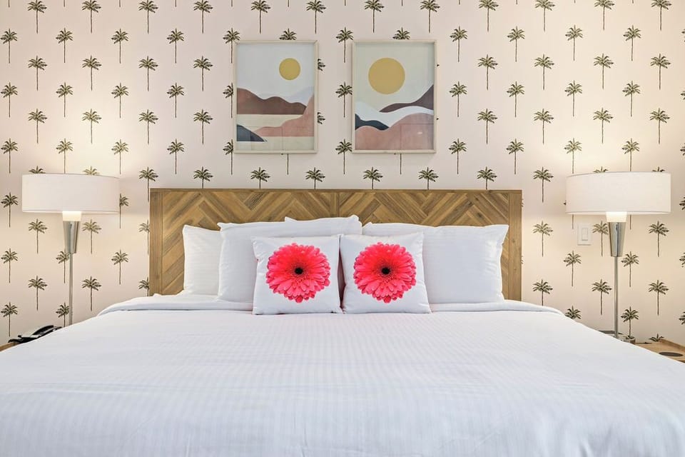 Sink into crisp, cloud-like linens on your plush bed, styled with cheerful accents and framed by tropical palm wallpaper and dreamy desert artwork.