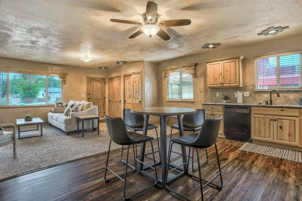 Unit B Cottage Kitchen - Pull up to the kitchen island with four barstools—great for coffee chats while someone cooks. Warm wood cabinets, dark appliances, and a big window keep it inviting.