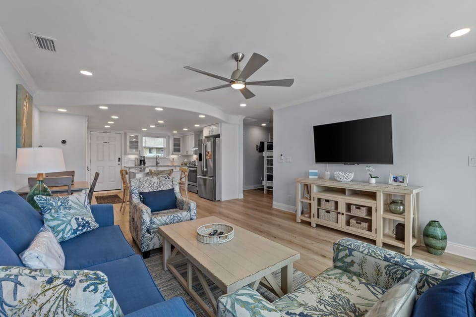 Relax in this bright, open living space with coastal charm. Plush seating, warm wood floors, and a ceiling fan await your arrival—perfect for unwinding after beach days.