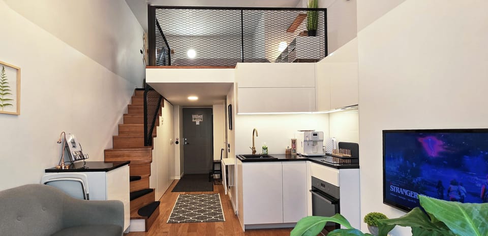 Split-level loft: mezzanine bed, stairs, kitchenette + TV nook.