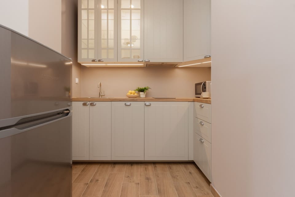 Another view of the kitchen, highlighting the clean countertops, ample storage, and minimalistic decor, maintaining a bright and functional space.