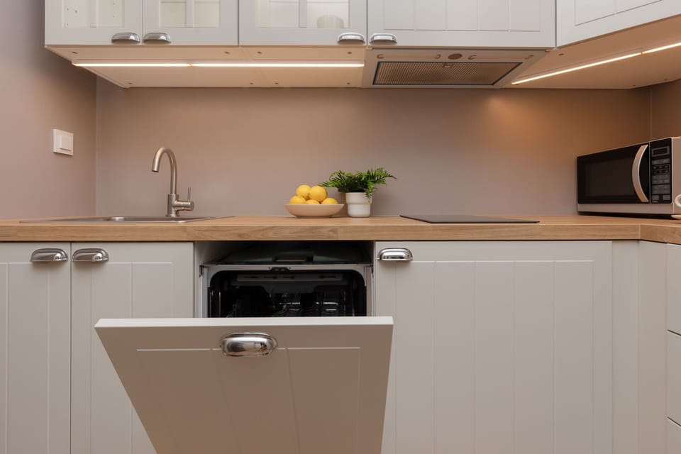 A sleek, modern kitchen with white cabinetry and a built-in oven, featuring clean lines and a soft, warm lighting scheme.