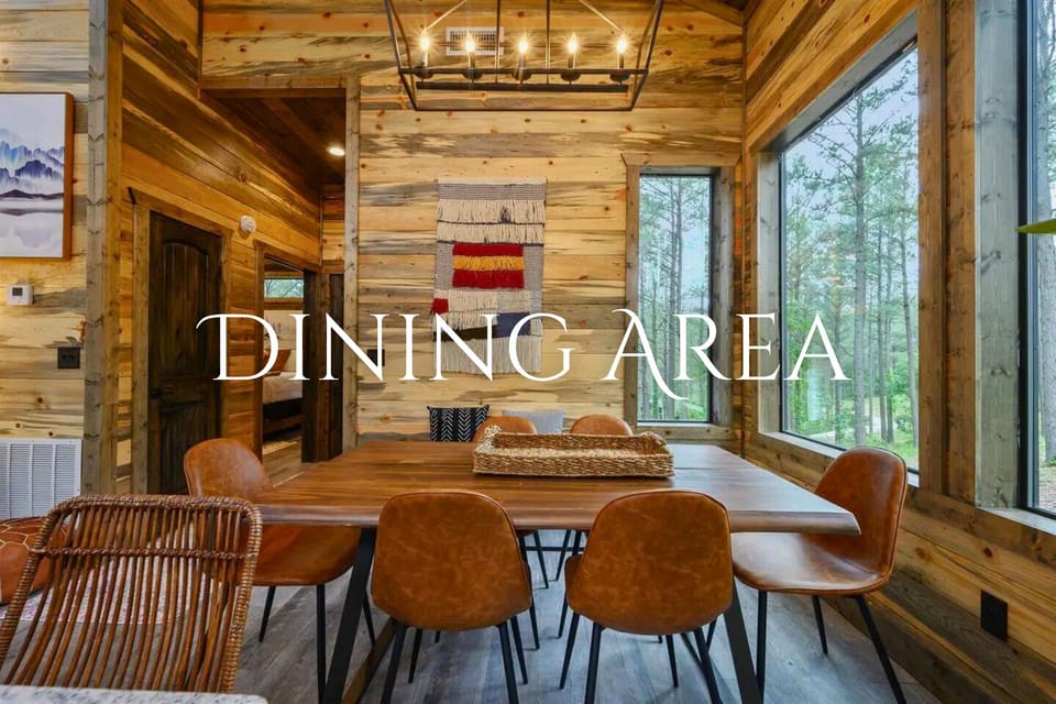 his dining space combines modern furniture with natural views, featuring a large wooden table surrounded by leather chairs under an artistic woven wall tapestry