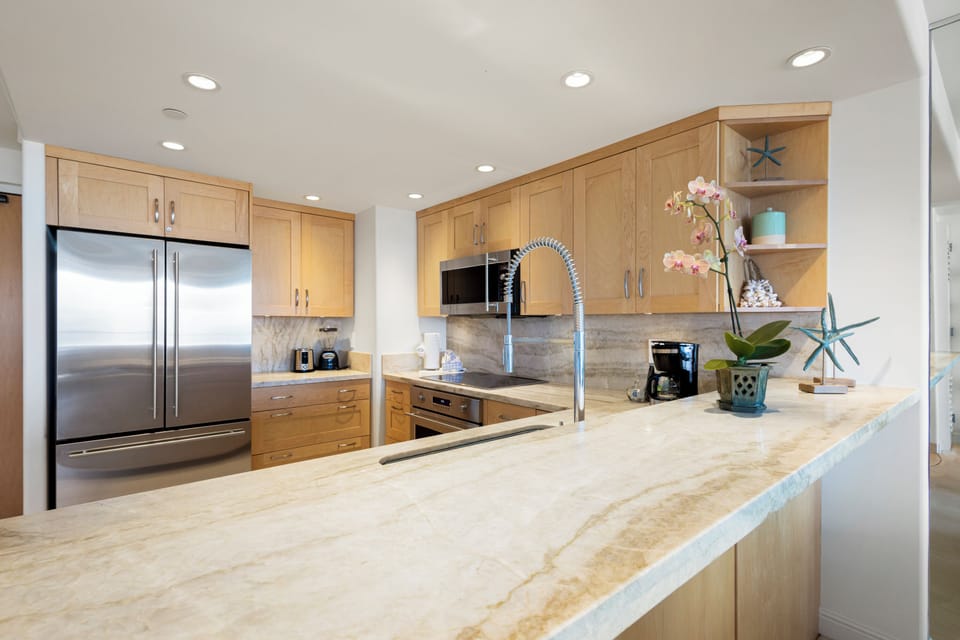 Cook comfortably in this spacious, well-equipped kitchen featuring stainless appliances, sleek countertops, and warm wood cabinetry—your perfect spot to create memorable meals.
