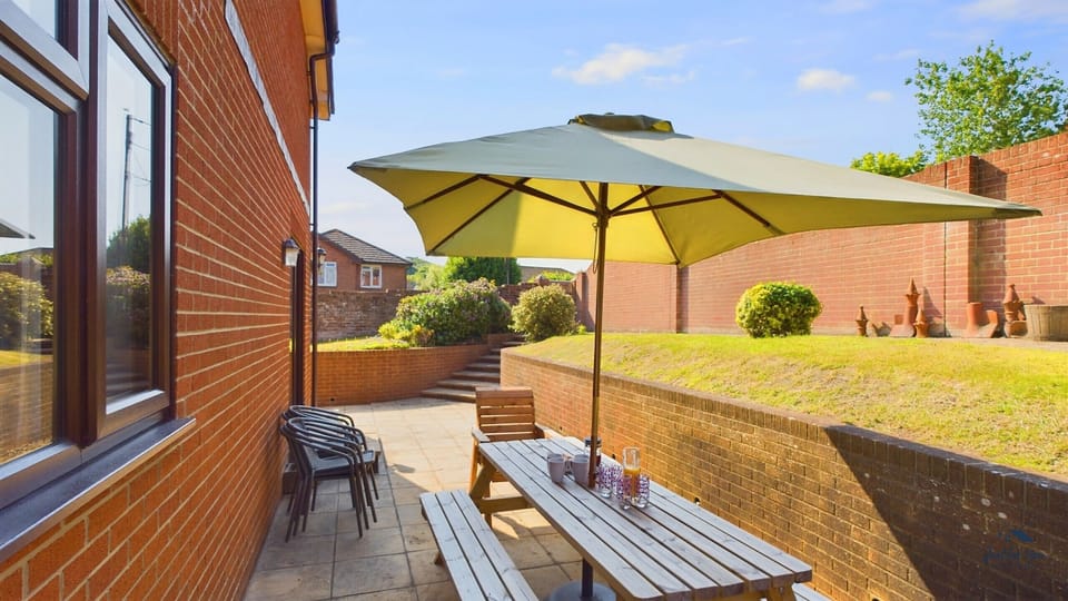 The private rear patio features a large dining set and parasol, ideal for summer holiday barbecues.
