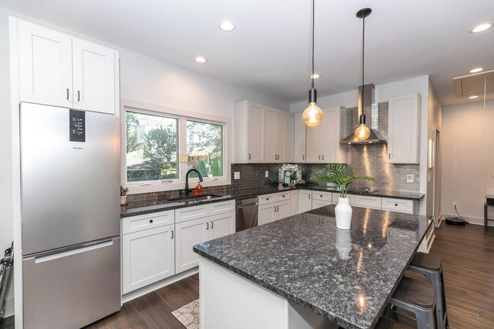 Bright, airy kitchen with a spacious island and sink under a sunlit window.