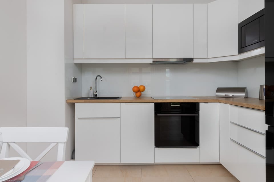 A contemporary open-plan kitchen equipped with white cabinets, a sleek countertop, and modern appliances. 