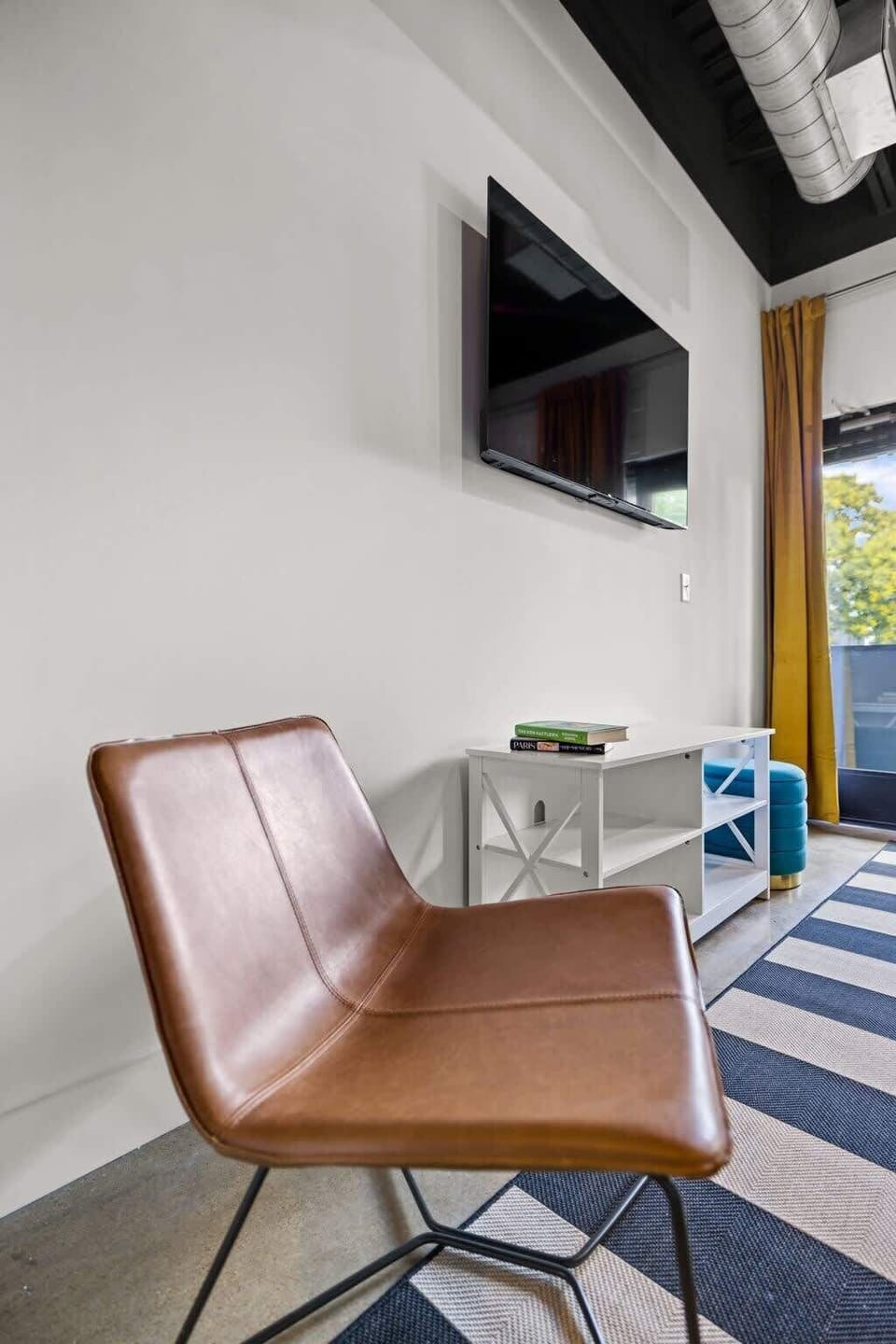 Experience the perfect blend of comfort and entertainment in our contemporary living room. The eye-catching striped rug adds a touch of sophistication, while the TV brings your favorite shows to life.