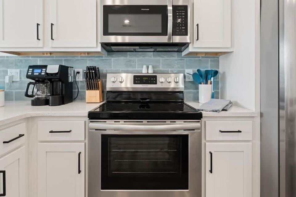 Cook, sip, and gather! This open-concept kitchen features brand-new appliances, full cookware, a drip/K-Cup coffee maker, and seating at both the dining table and bar