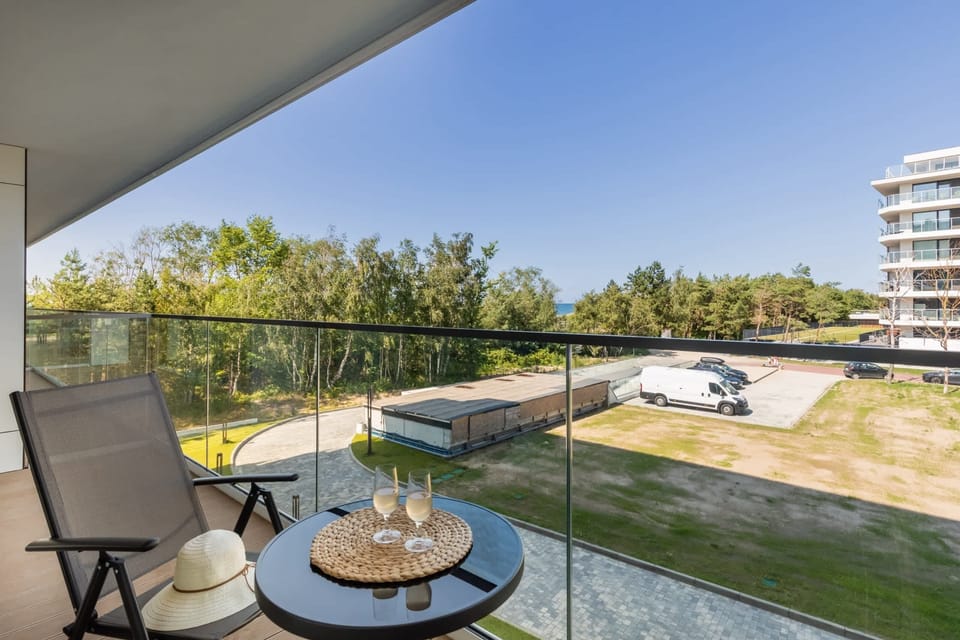 A spacious balcony with outdoor seating and a relaxing view of the surrounding green landscape.