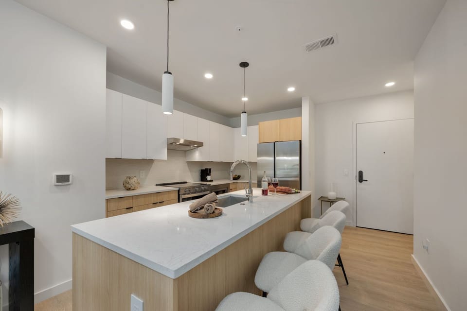 Fully equipped modern kitchen stocked with all culinary essentials and featuring brand new stainless steel appliances with an island offering bar seating.