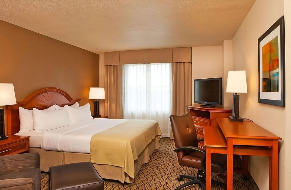 Unwind in a crisp king bed with warm lighting.