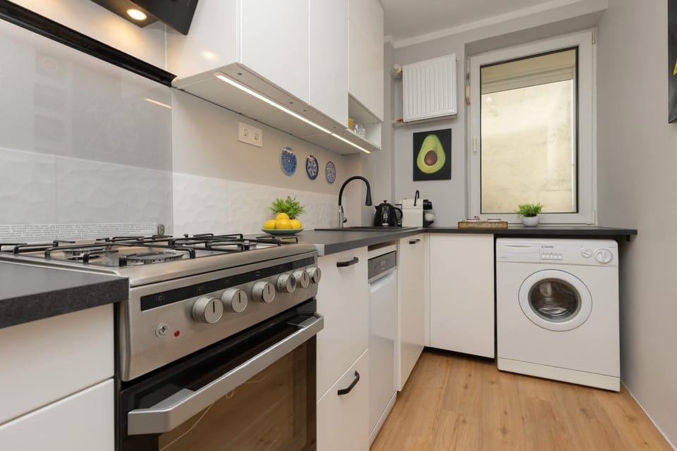 A modern kitchen with a gas stove, oven, and washing machine, offering convenience and practicality.

