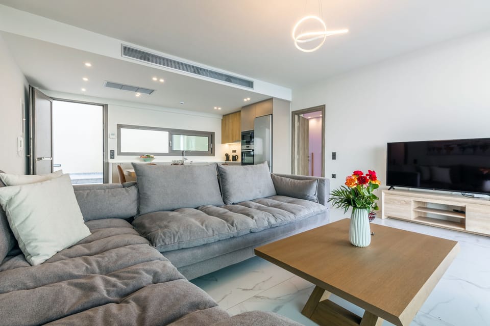 The living room features a plush corner sofa and a 55’’ smart TV, perfect for relaxing evenings.