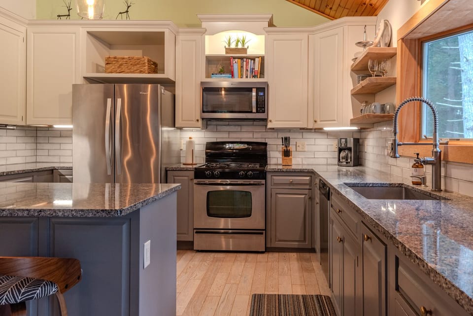 Uniquely illuminated kitchen equipped with floating shelves and granite counters