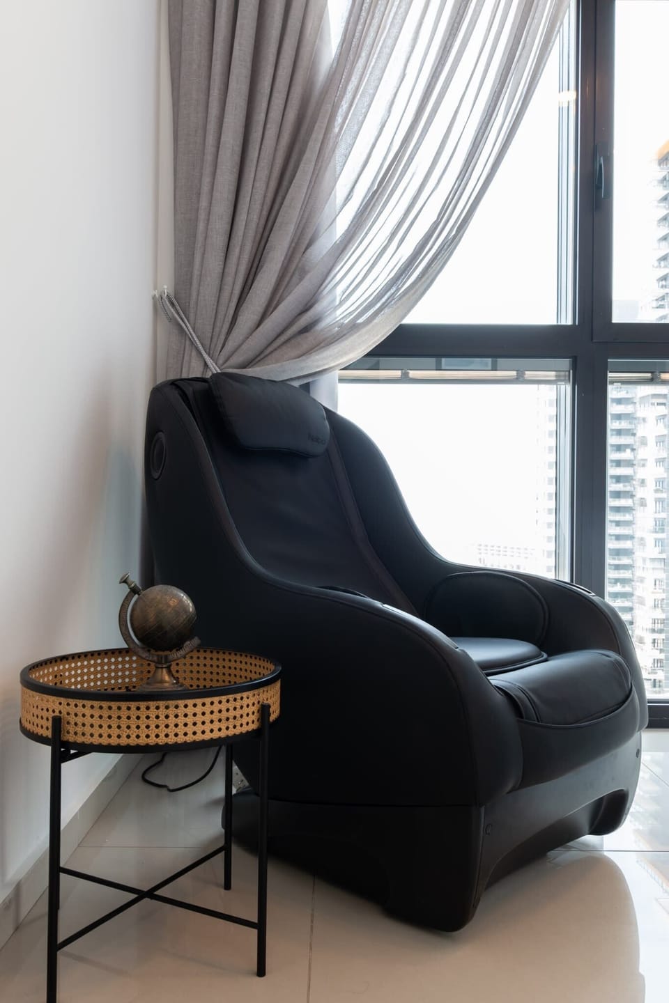 Cozy reading chair by window offers quiet retreat, ideal for relaxing with city and ocean views.