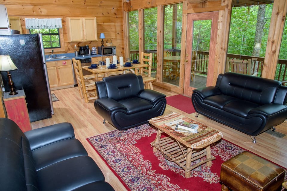 Open concept kitchen, dining, and living areas of the cabin with gorgeous views of the hillside forest. 
