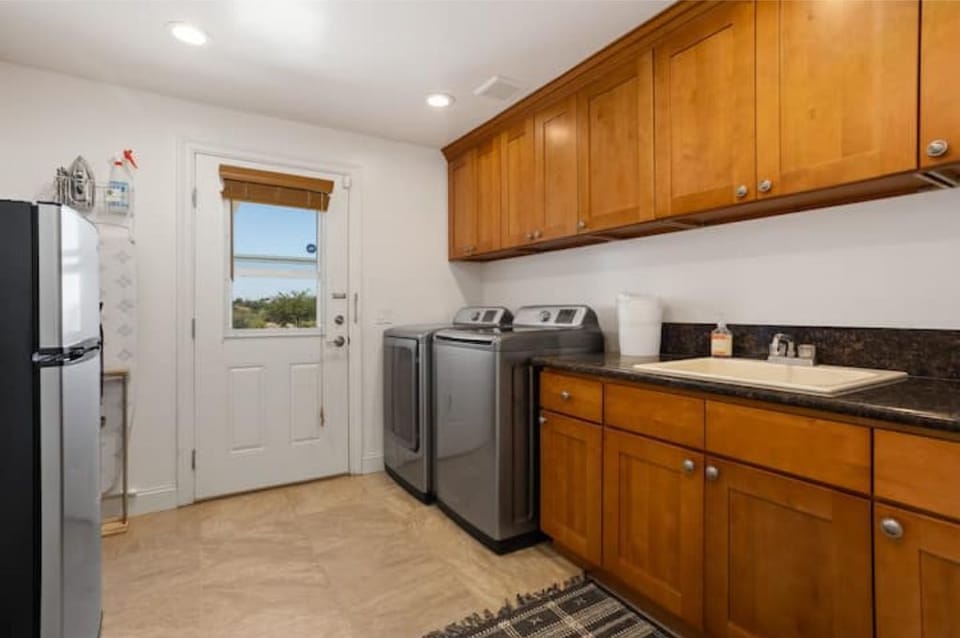 Main floor laundry room with full-size washer/dryer, sink, iron, and iron board.
