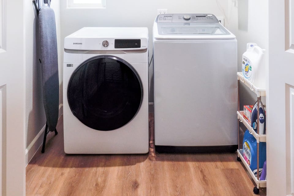 In-unit laundry area with washer and dryer and laundry essentials.