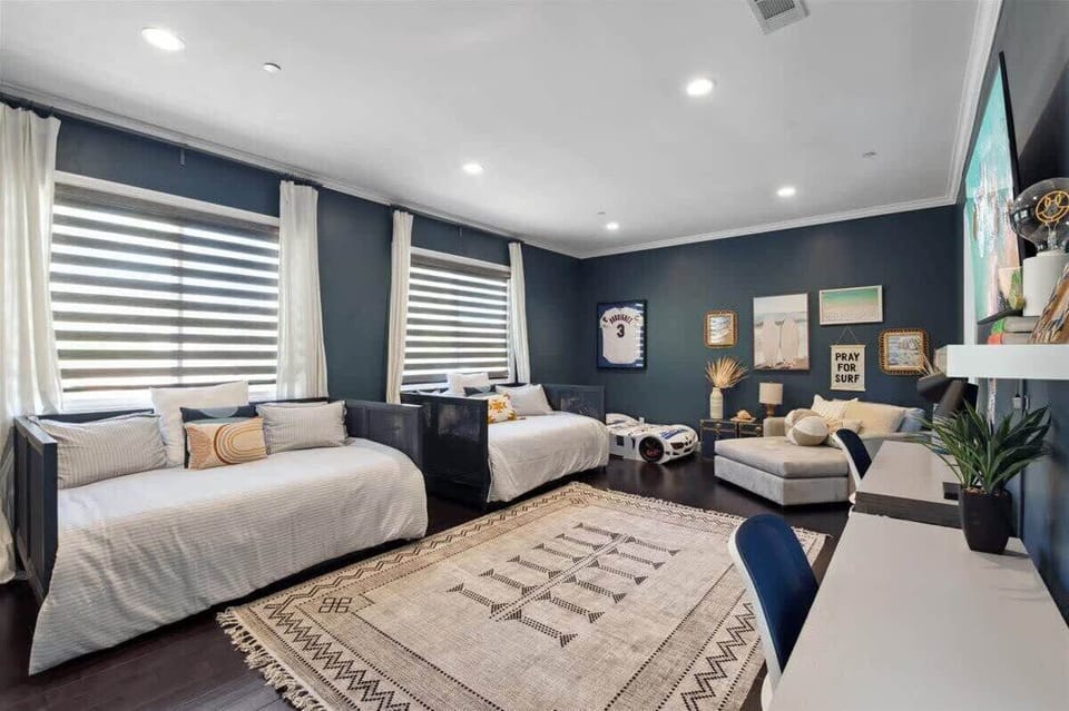 Upstairs kids' room featuring five beds, two desks, and a large TV—plenty of space for sleep and play.