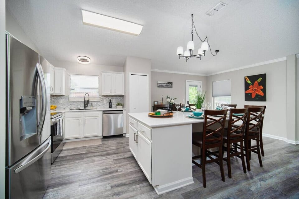 Modern kitchen with stainless steel appliances, large island, and open dining area.