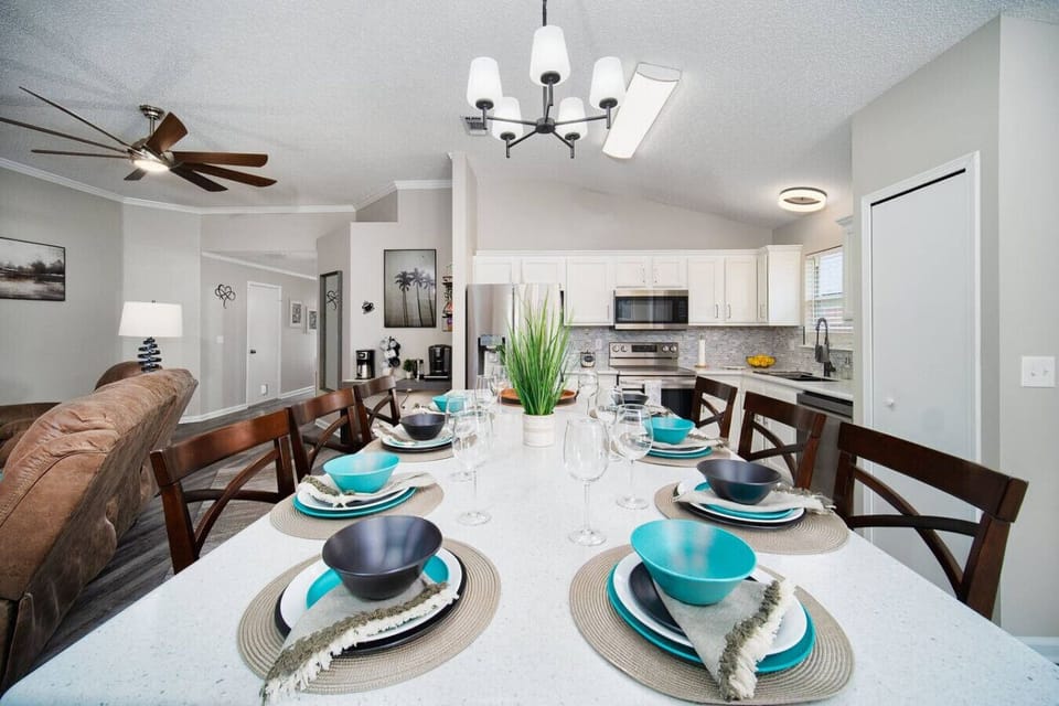 Beautifully set dining area with modern decor, adjacent to a spacious kitchen and cozy living room.