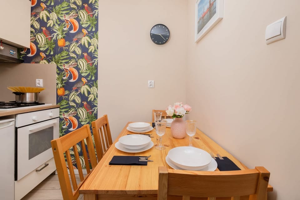 A compact kitchen with modern appliances, a colorful accent wall, and a cozy dining nook for two.

