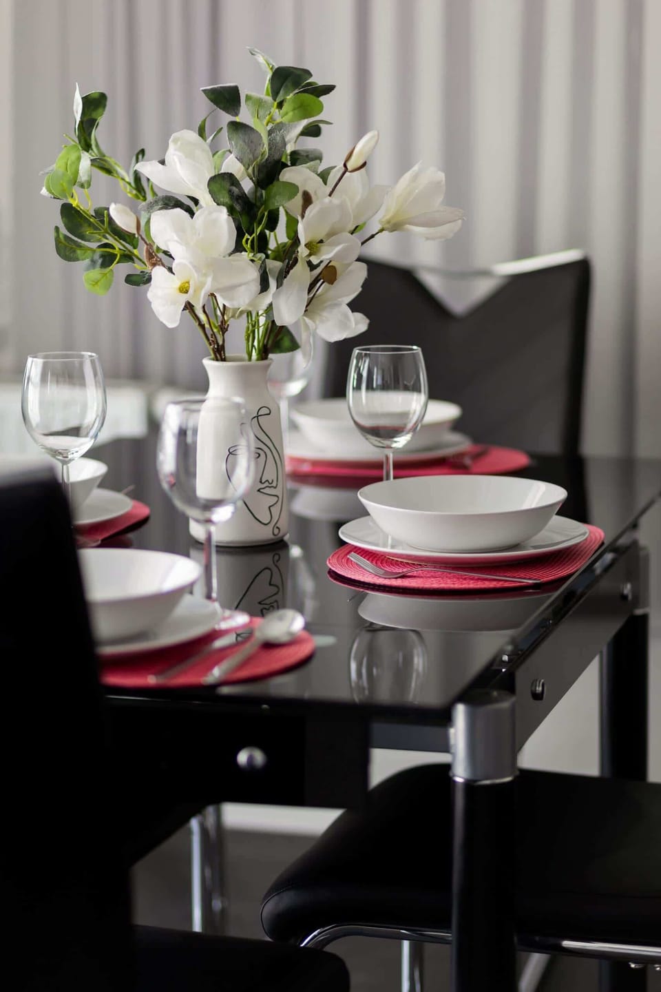 A stylish dining setup with modern chairs, a beautifully set table, and large windows allowing natural light.

