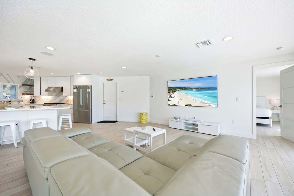 Modern open living area with a large leather sectional and wall-mounted television.