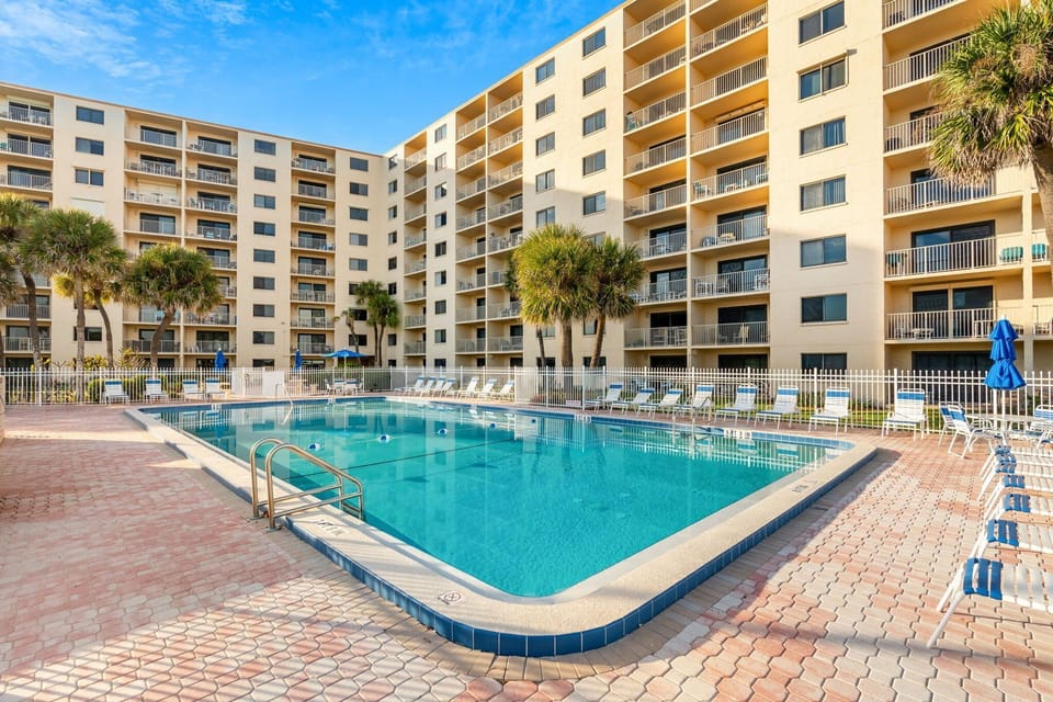Inviting outdoor heated pool area surrounded by lush greenery and lounge seating.