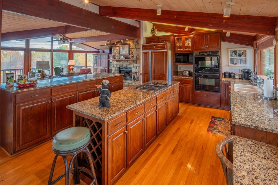 Kitchen with granite countertops, wooden cabinets, and island seating.