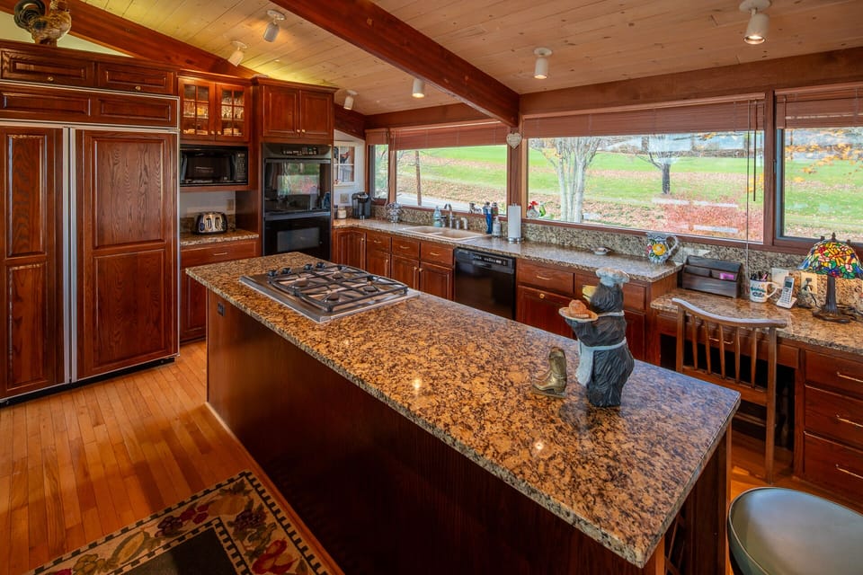 Kitchen with granite countertops, wood cabinets, and cooktop island.