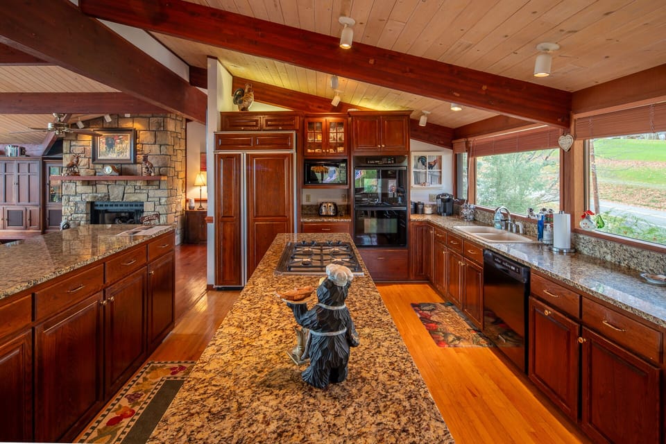 Kitchen with granite countertops, wooden cabinets, and cooktop island.