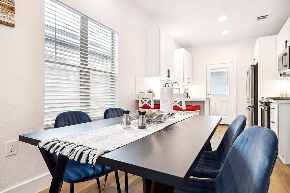 Bright dining space with modern blue chairs and a sleek table. Perfect for enjoying meals together or working in a comfortable, well lit setting.