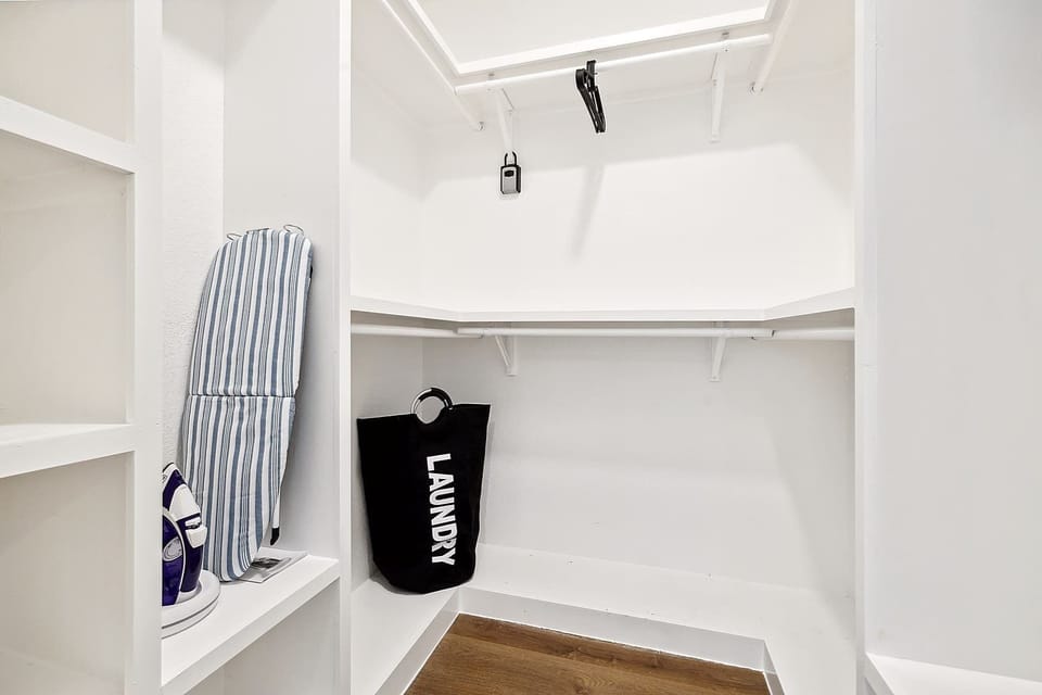 Spacious laundry and storage nook with shelving and hanging space. Perfect for organizing clothes and essentials during your stay.
