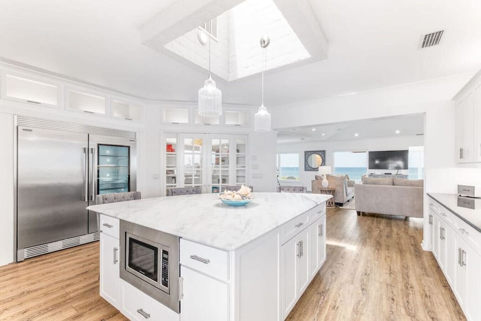 Natural light floods in through the skylight above.  The kitchen island features stone countertops and a built-in microwave.