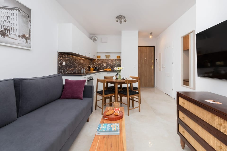 A spacious living and dining area with a gray sofa, wooden furniture, and modern decor for a functional and inviting layout.


