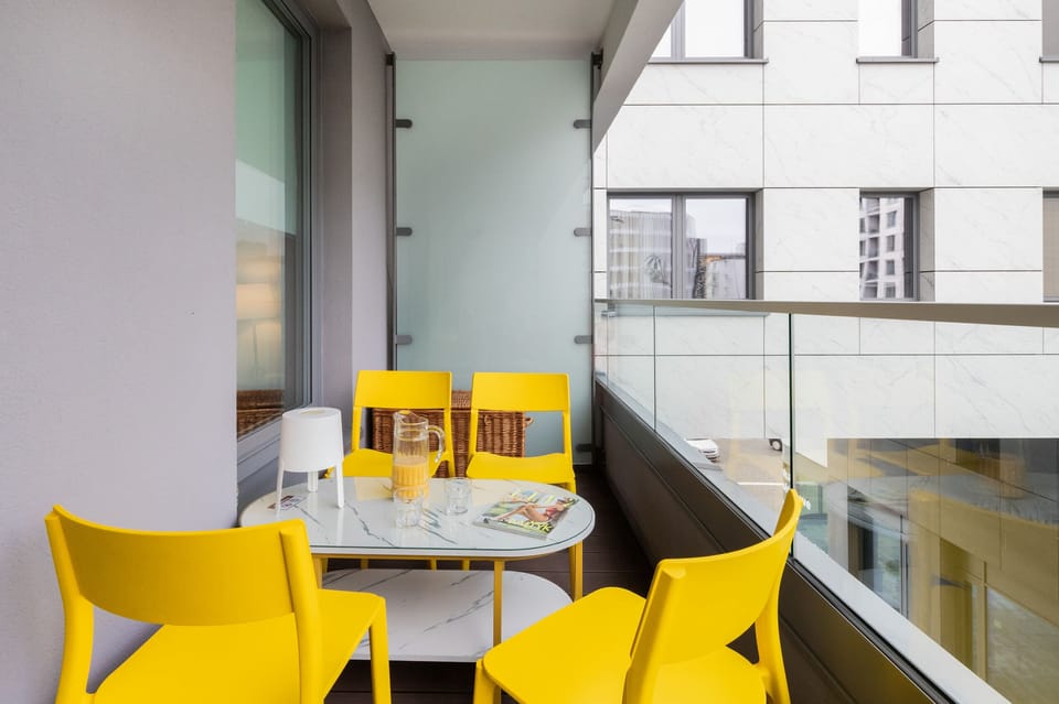 A cozy balcony with a vibrant yellow dining set, perfect for enjoying outdoor meals with a view of the surroundings.

