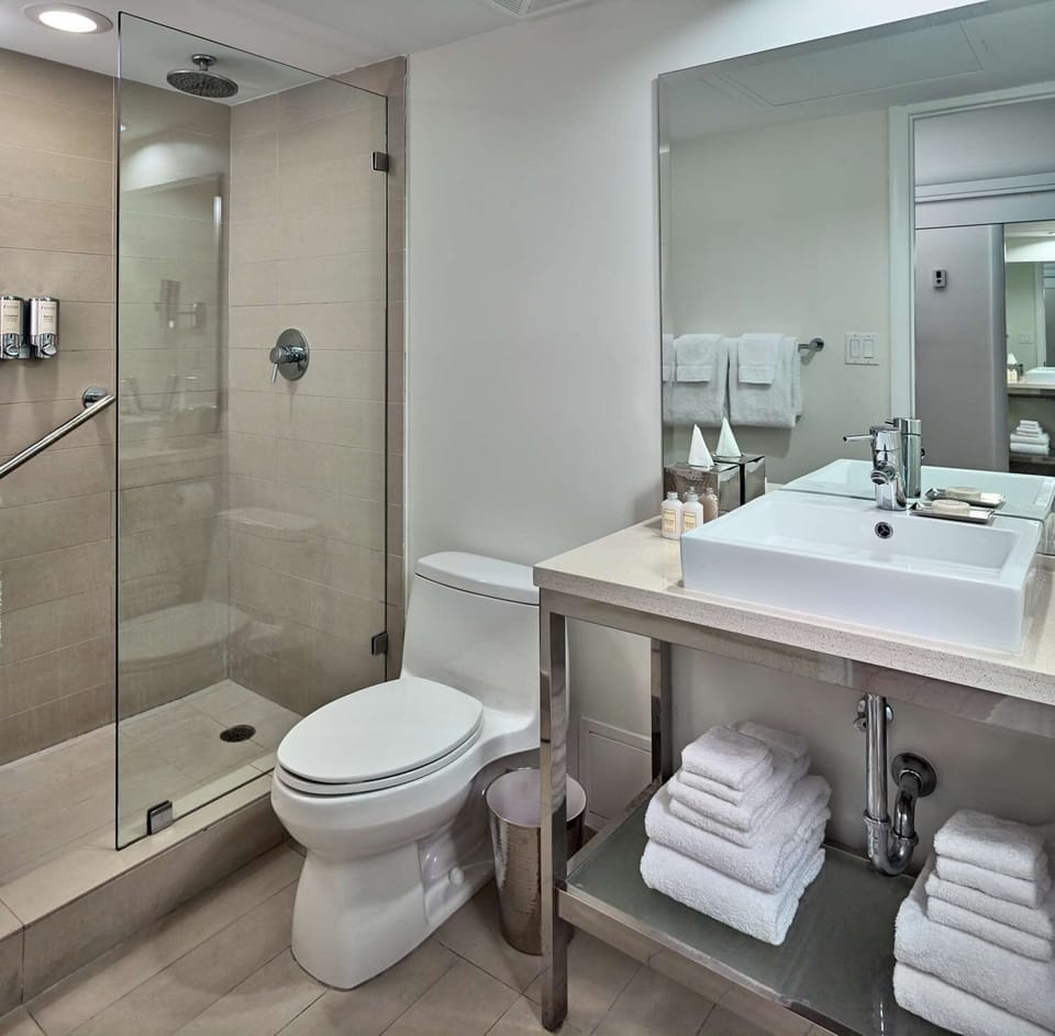 Refresh in a spotless bath with glass shower and fluffy towels.
