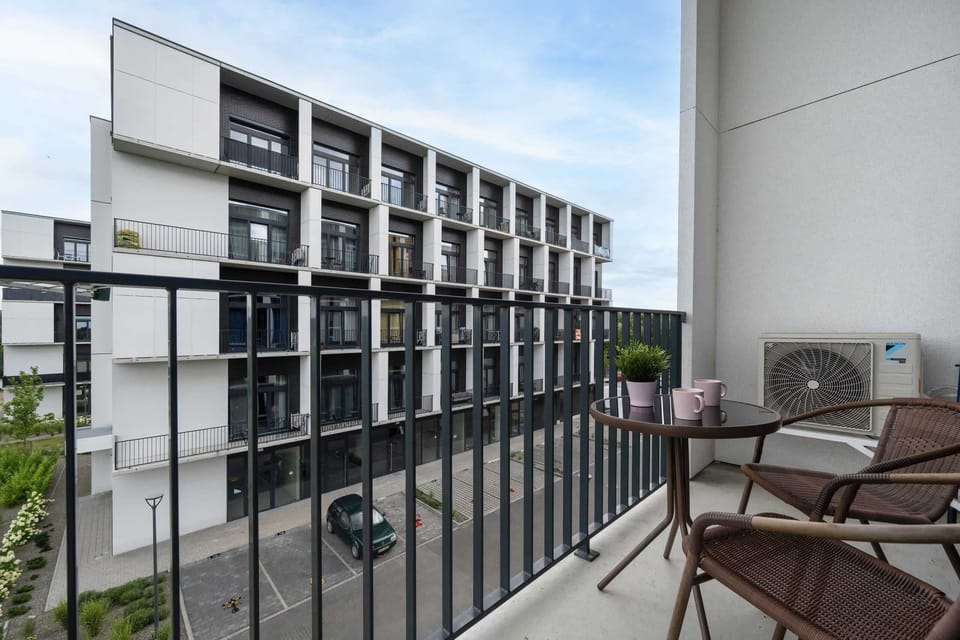 A private balcony with outdoor seating, offering a view of the surrounding residential area.

