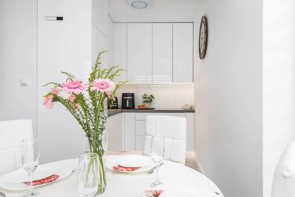 A dining area with a white table and chairs, complemented by a vase of fresh flowers for a cheerful touch.

