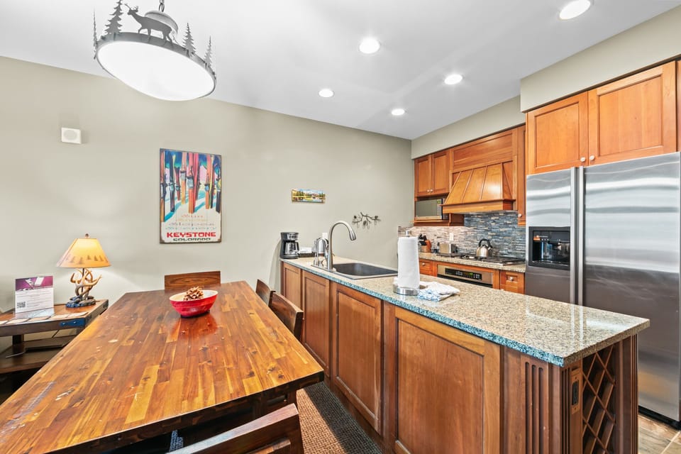 Your fully equipped kitchen features warm wood cabinetry, granite countertops, and stainless steel appliances, perfect for preparing mountain meals together.