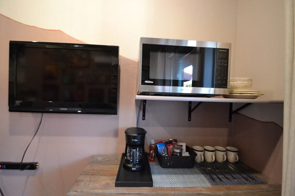A TV with Roku, a microwave, and complimentary snacks/coffee.