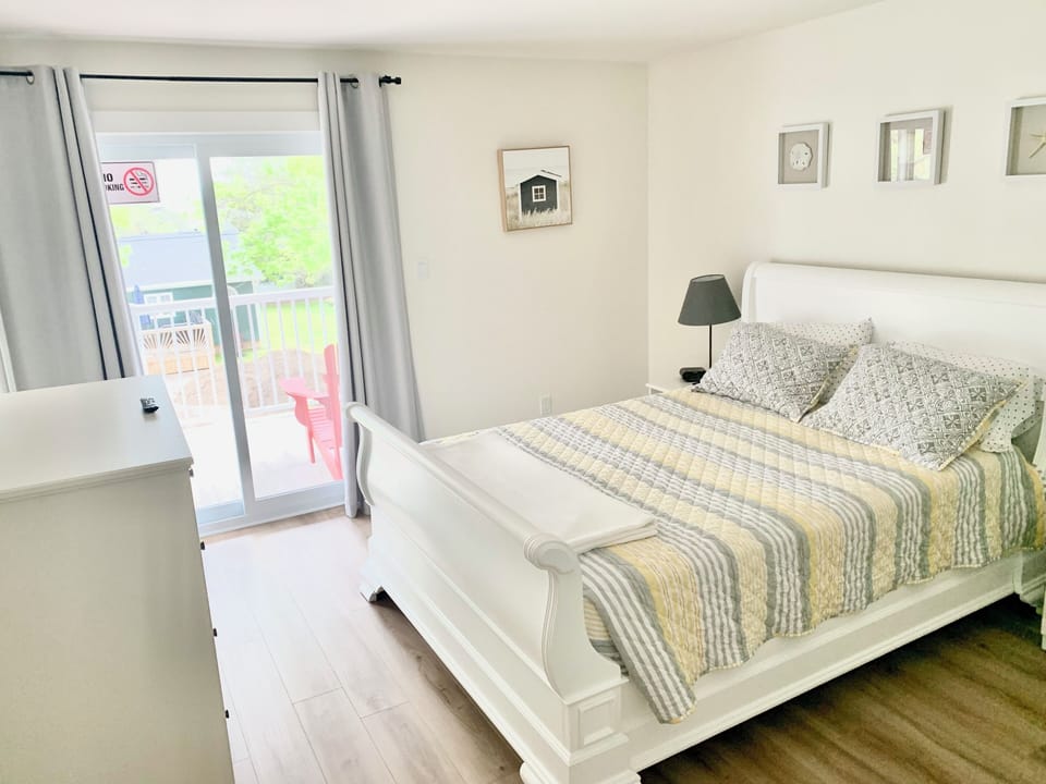Upstairs queen bed with TV, closet, dresser and balcony access.