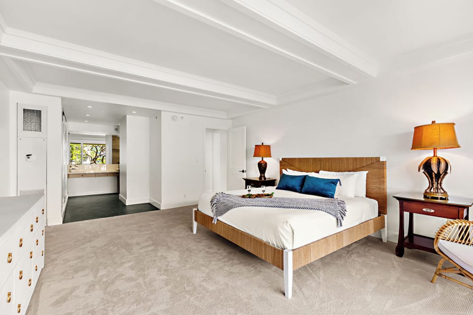 Spacious island-inspired retreat featuring a comfortable king-size bed, rich wood furnishings, cozy tropical accents, and a bright inviting bedroom space.